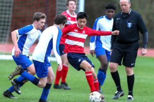 Teenage boarding school boys playing football on the pitch