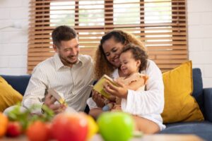 Two smiling parents reading to their child