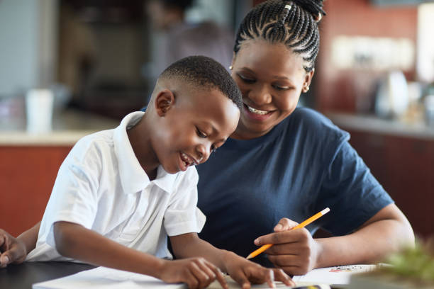 An African mother smiling with her son as she helps him with some effective study habits.